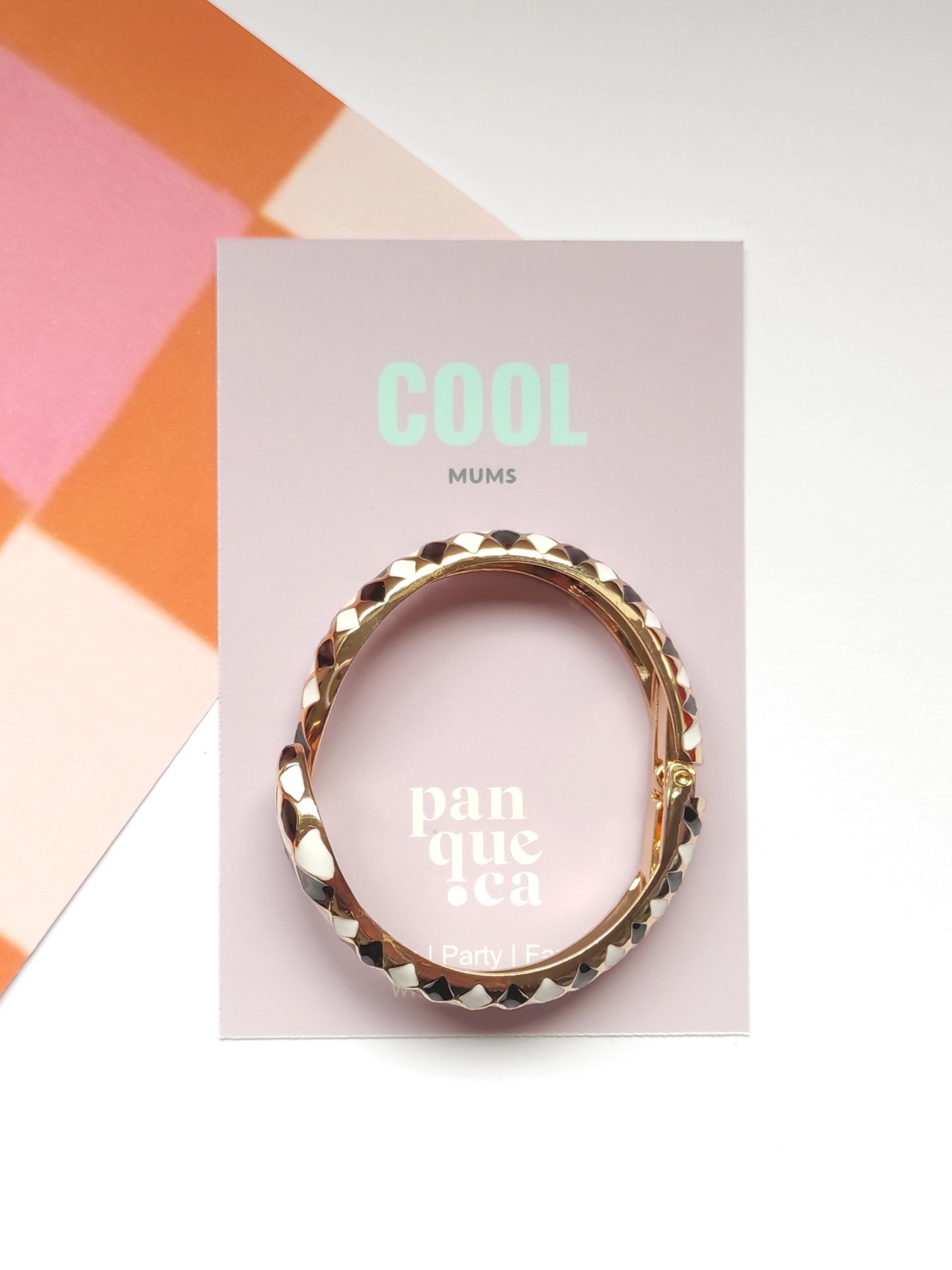 Pulseira dourada texturizada sobre cartão de apresentação cor-de-rosa claro