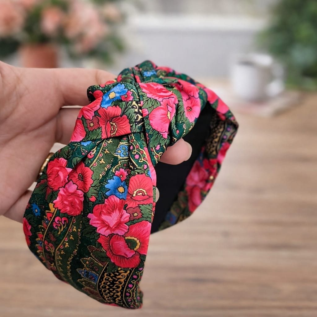 Faixa de cabelo com padrão floral colorido segurada por mão feminina