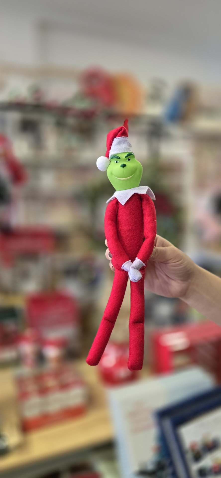 Boneco do Grinch com chapéu de Natal vermelho e roupagem vermelha em fundo desfocado