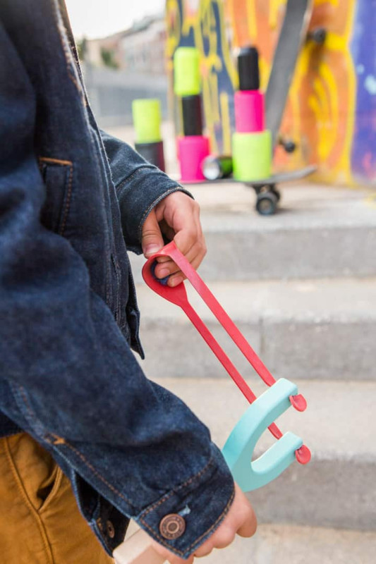Pessoa com camisa de ganga segurando instrumento azul com bandas elásticas vermelhas