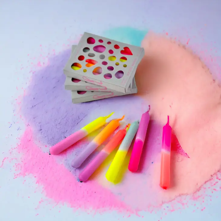 Velas coloridas com suportes metálicos sobre pó colorido