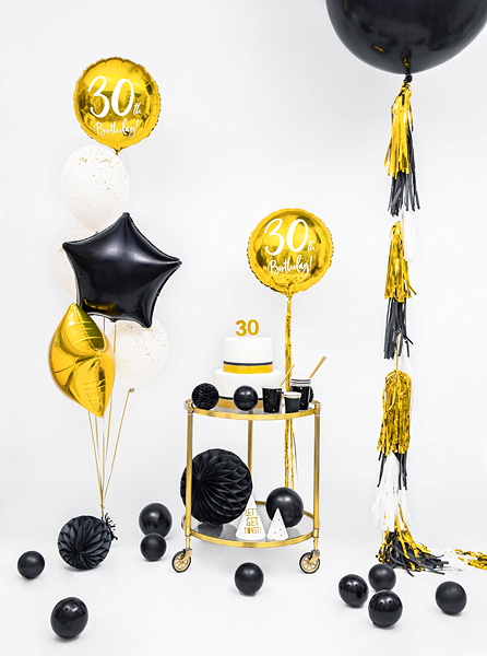 Decoração para 30º aniversário com balões dourados, pretos e brancos, bolo branco com número 30, copos pretos e palhinhas, e carrinho dourado em fundo branco