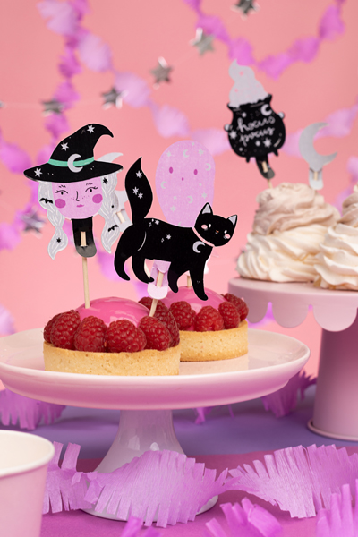 Tartes decoradas com figuras de Halloween em pratos brancos em ambiente festivo cor-de-rosa