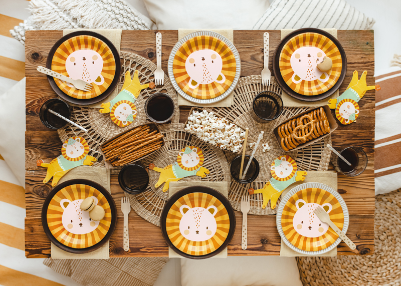 Mesa posta com pratos e jogos americanos de leão, talheres e petiscos