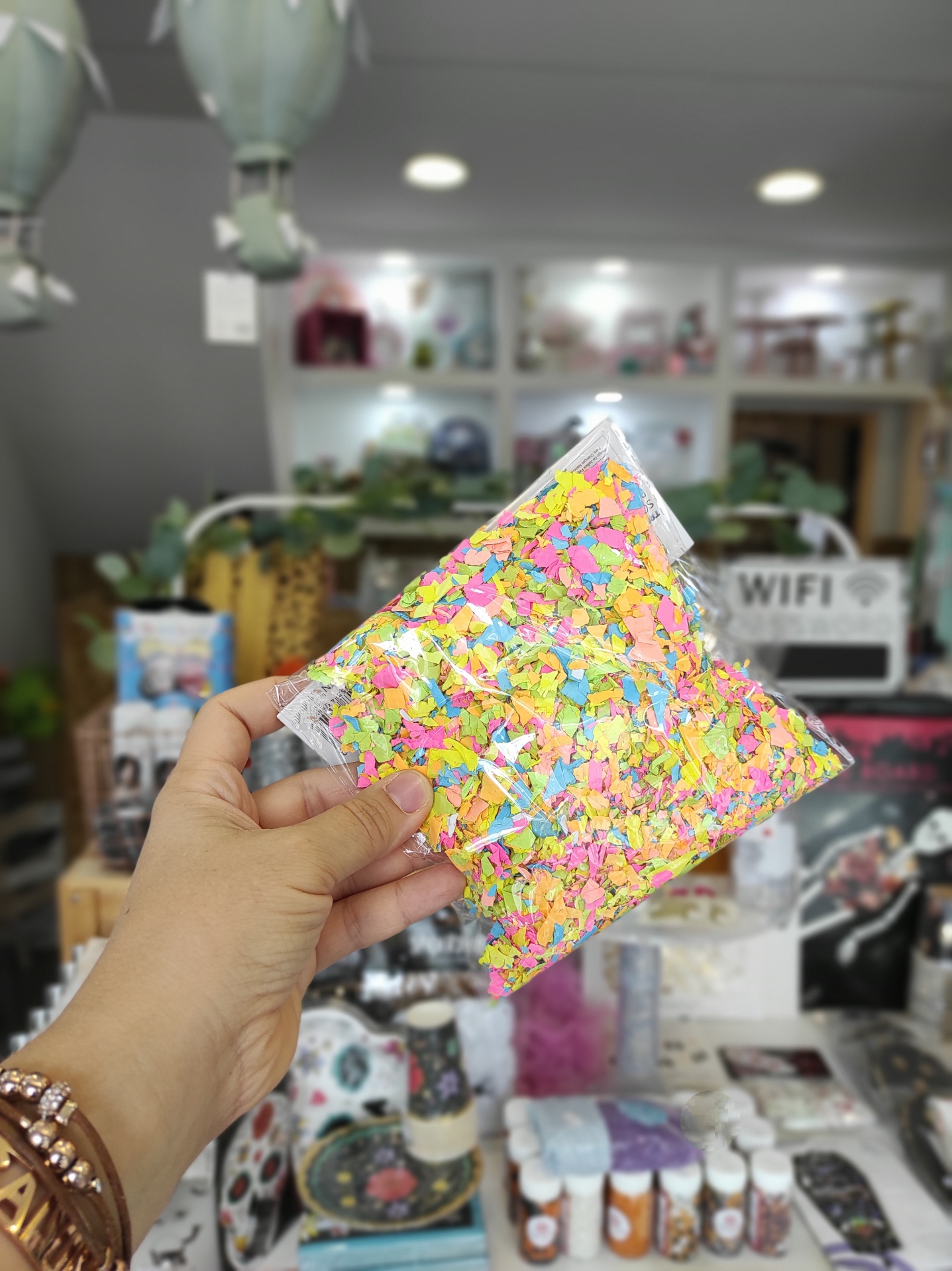 Saco plástico com confetes coloridos segurado por mão em loja