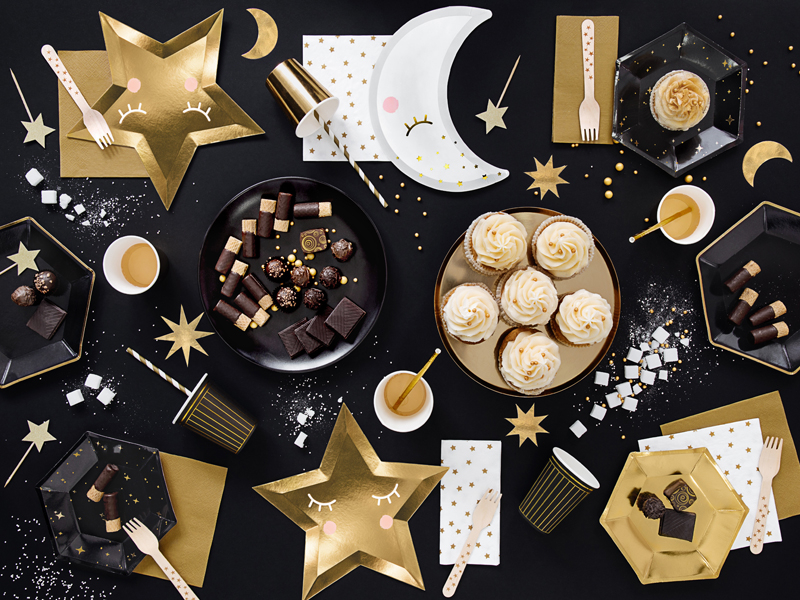 Pratos de papel decorativos com tema de estrela e lua, cupcakes, chocolates e utensílios de festa em fundo preto com estrelas e luas douradas.