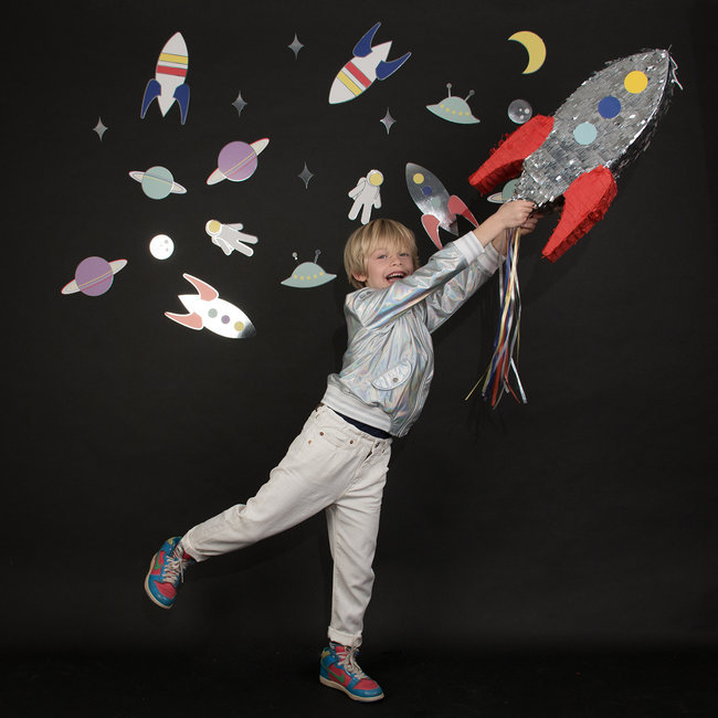 Criança a brincar com foguete e adesivos espaciais num fundo preto