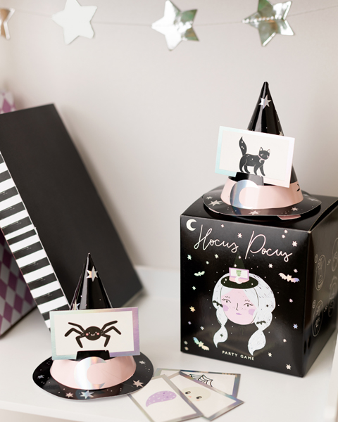 Dois chapéus de festa em papel com cartões e caixa de jogo de festa preto com ilustração e texto