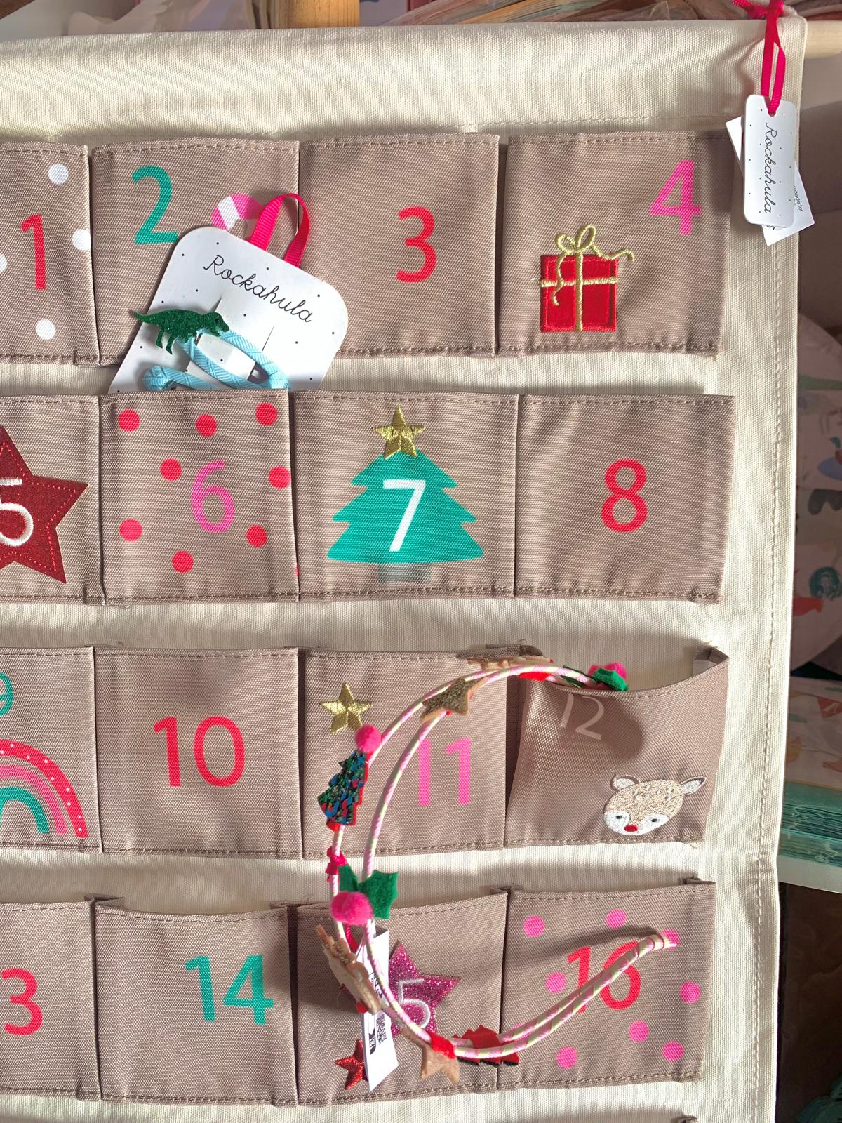 Calendário do advento em tecido bege com bolsos numerados e desenhos festivos