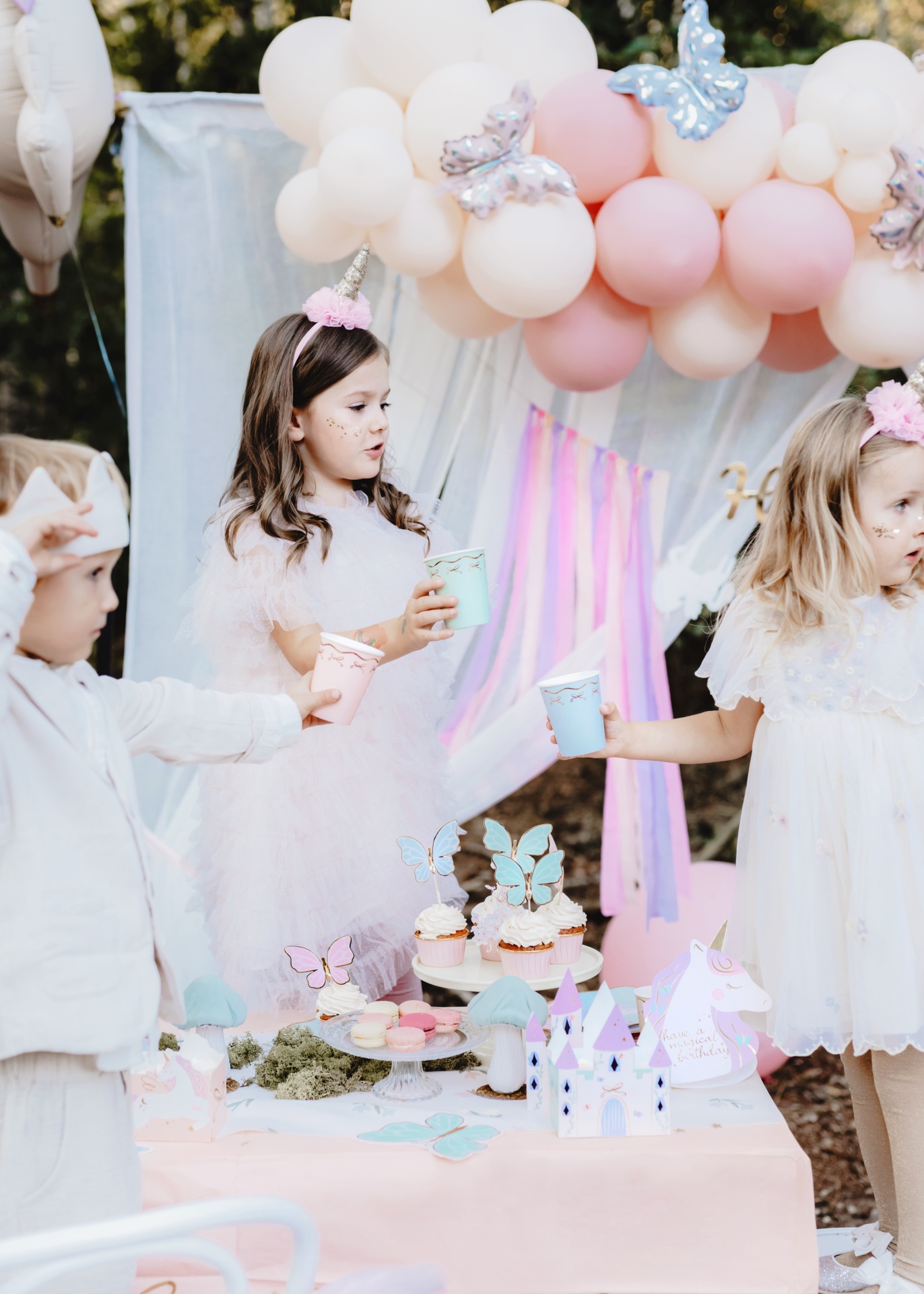Crianças em festa infantil ao ar livre com decoração de unicórnio e balões