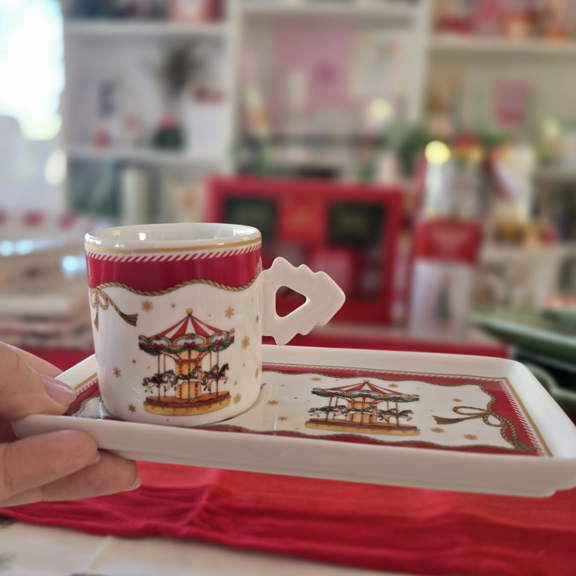 Conjunto de chávena e prato de porcelana com padrão de carrossel e bordas vermelhas.