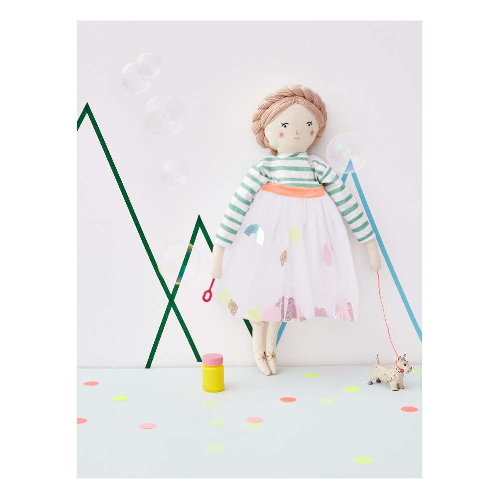 Boneca de tecido com vestido colorido e cão de brinquedo em fundo com formas geométricas