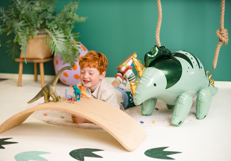 Criança brinca com dinossauros brinquedo e balão insuflável dinossauro