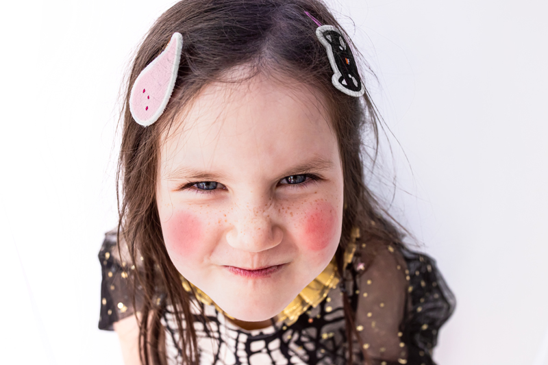 Menina sorridente com ganchos de cabelo coloridos e vestido quadriculado