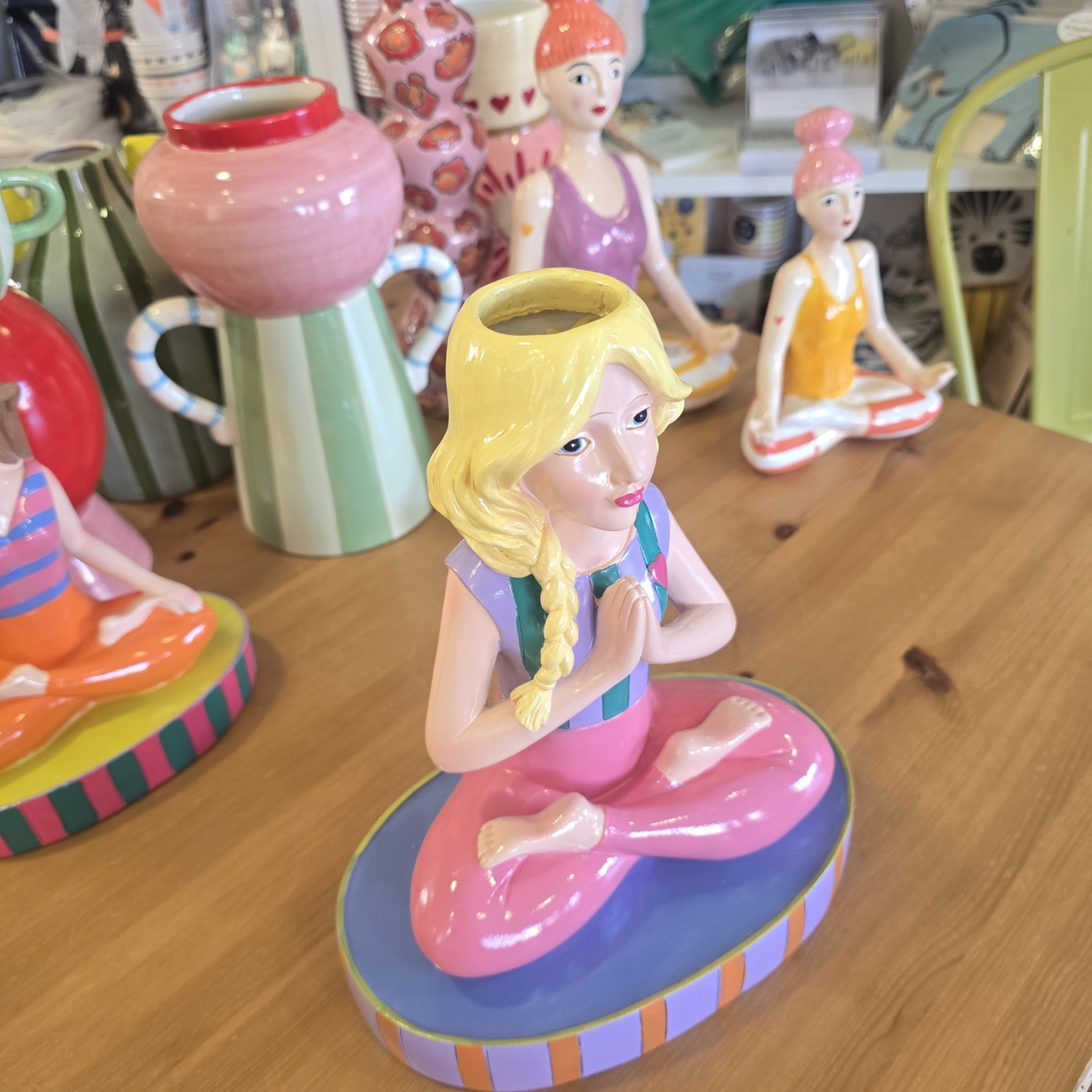 Figuras de mulheres a meditar em cerâmica colorida numa mesa de madeira