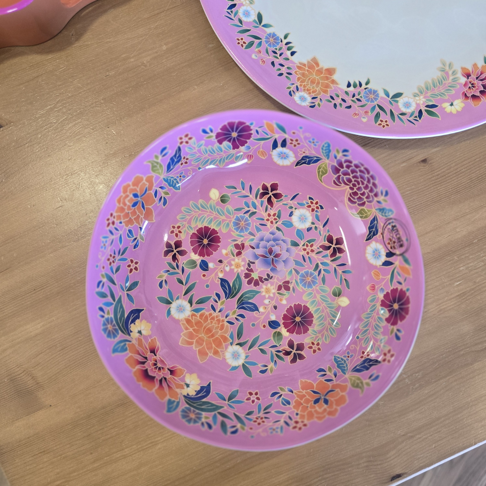 Prato fundo rosa com padrão floral colorido sobre mesa de madeira