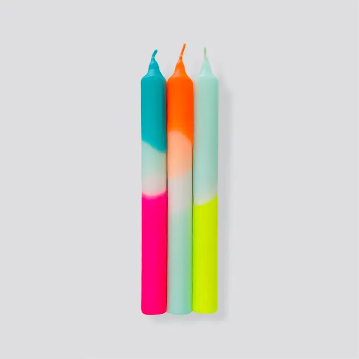 Três velas coloridas com design em três tons sobre fundo cinzento