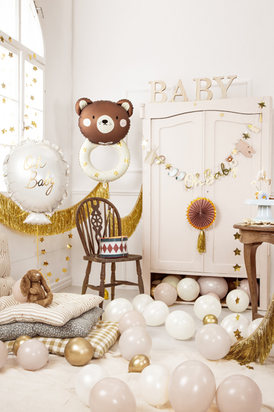 Decoração de festa para bebé com balões e elementos decorativos em tons neutros e dourado