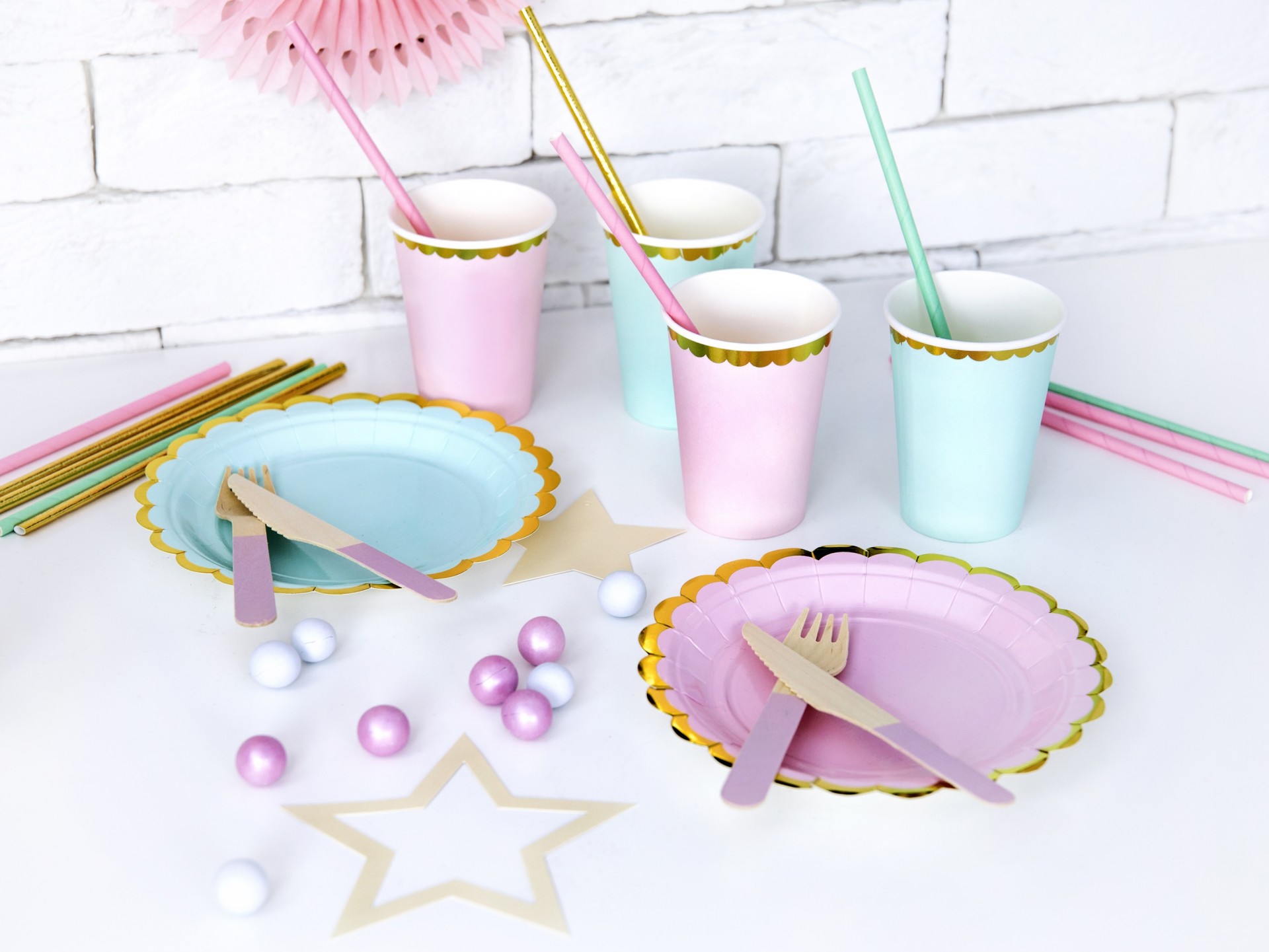 Conjunto de copos e pratos coloridos para festa com talheres e canudos sobre mesa branca