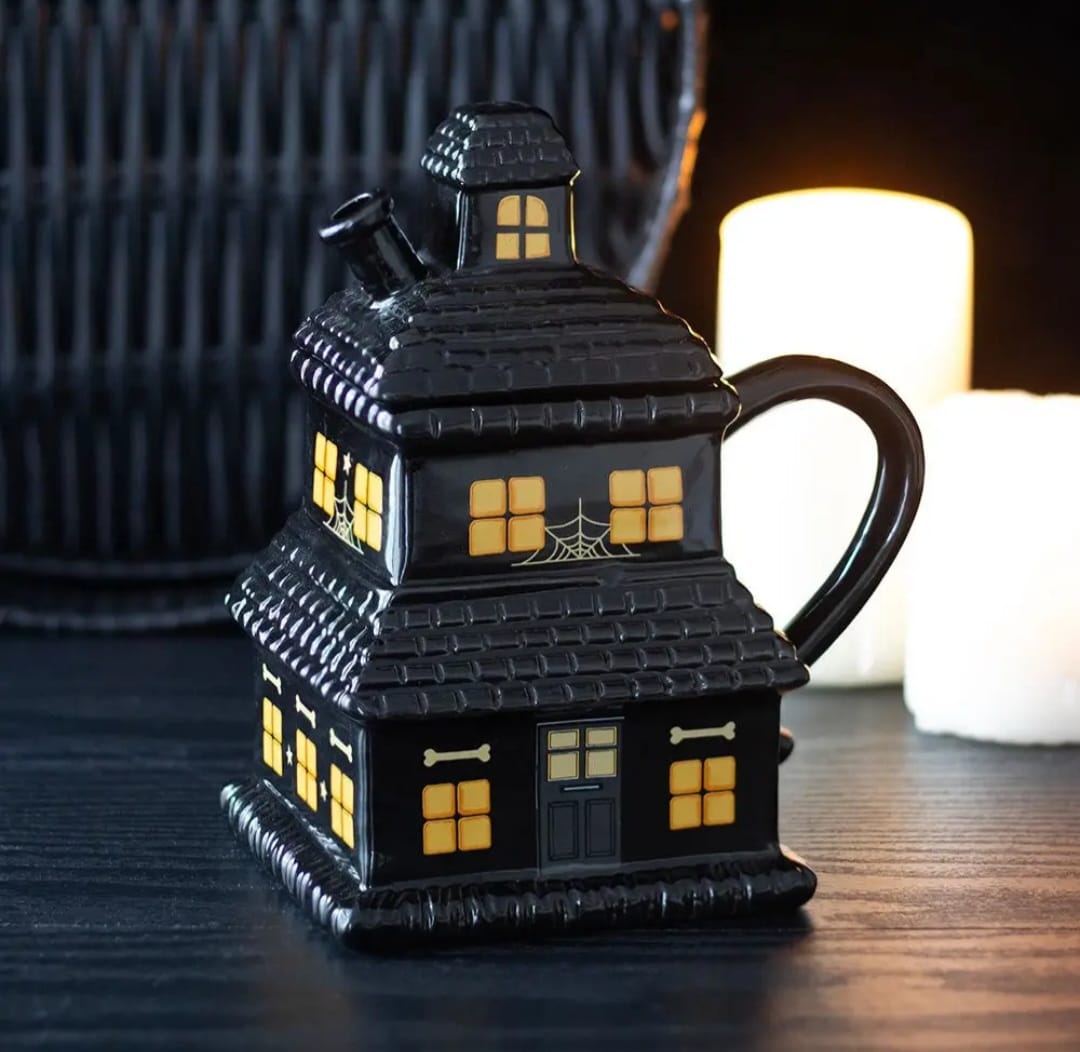 Caneca preta de cerâmica em forma de casa com janelas amarelas e decoração de Halloween