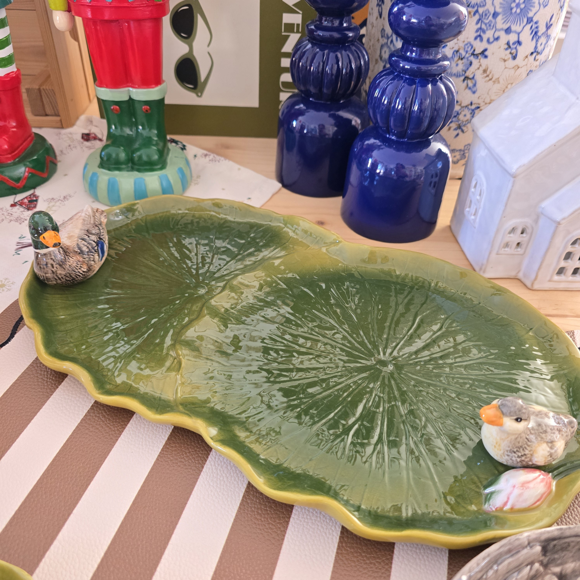 Prato decorativo verde em cerâmica com patos e outros objetos decorativos numa mesa