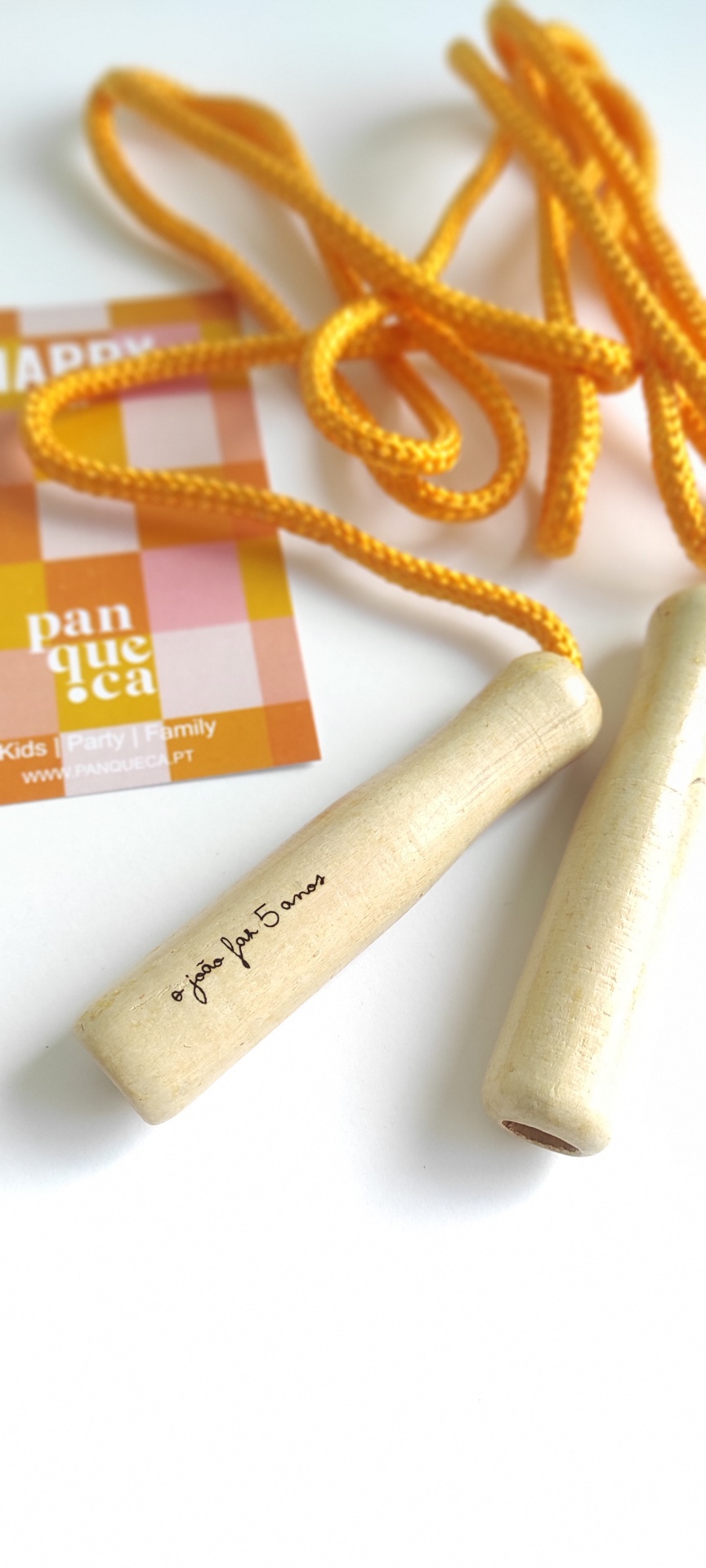 Corda de saltar com pega em madeira e corda amarela sobre fundo branco