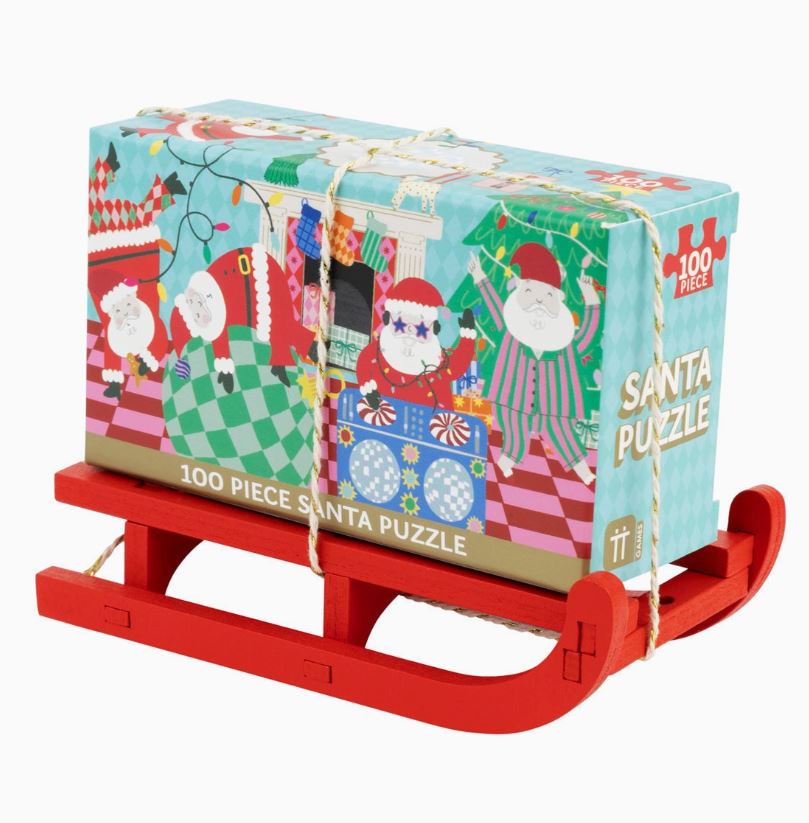 Quebra-cabeças de Natal com 100 peças em caixa colorida sobre trenó vermelha de madeira.