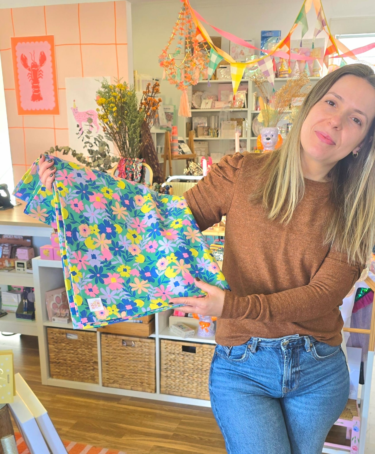 Mulher segurando tecido com padrão floral colorido numa loja decorada