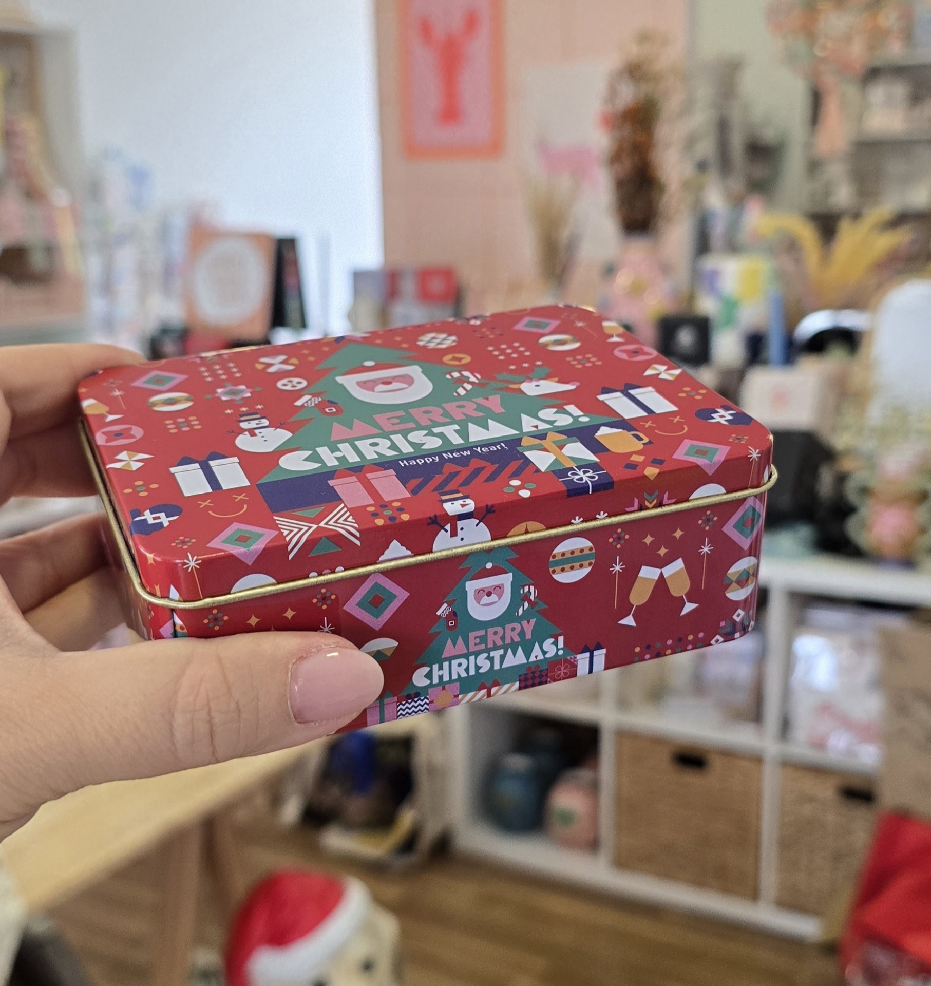 Caixa metálica vermelha com design de Natal e texto MERRY CHRISTMAS!