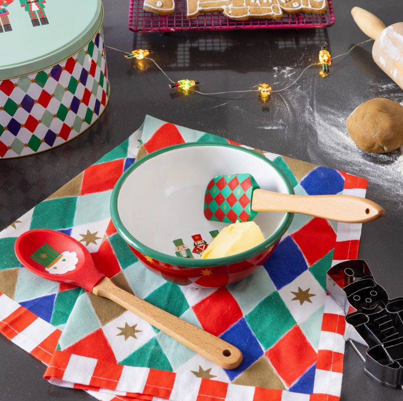 Utensílios de cozinha natalícios com tigela, espátula, colher de pau e toalha quadriculada