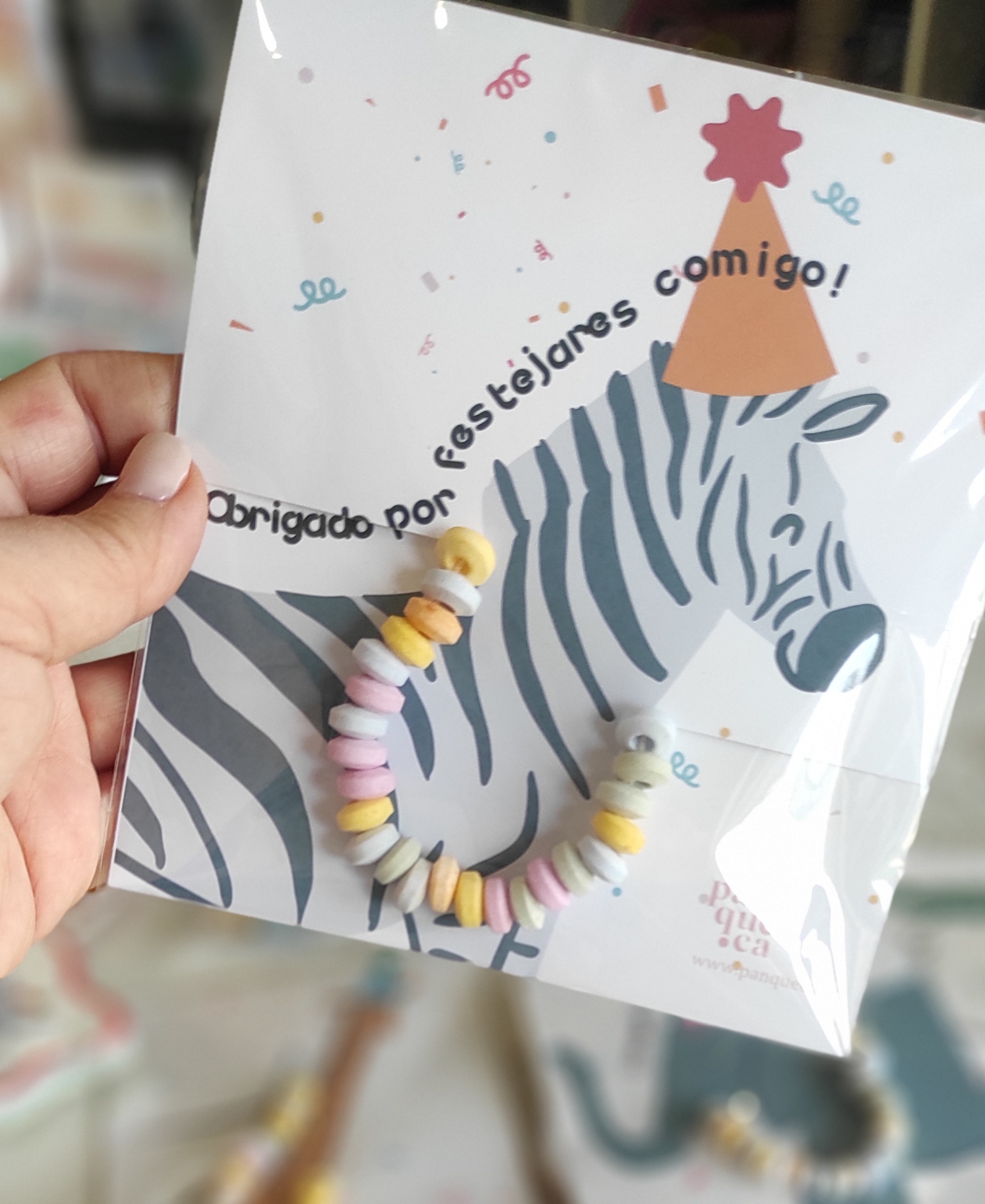 Pulseira colorida em embalagem com imagem de zebra com chapéu de festa