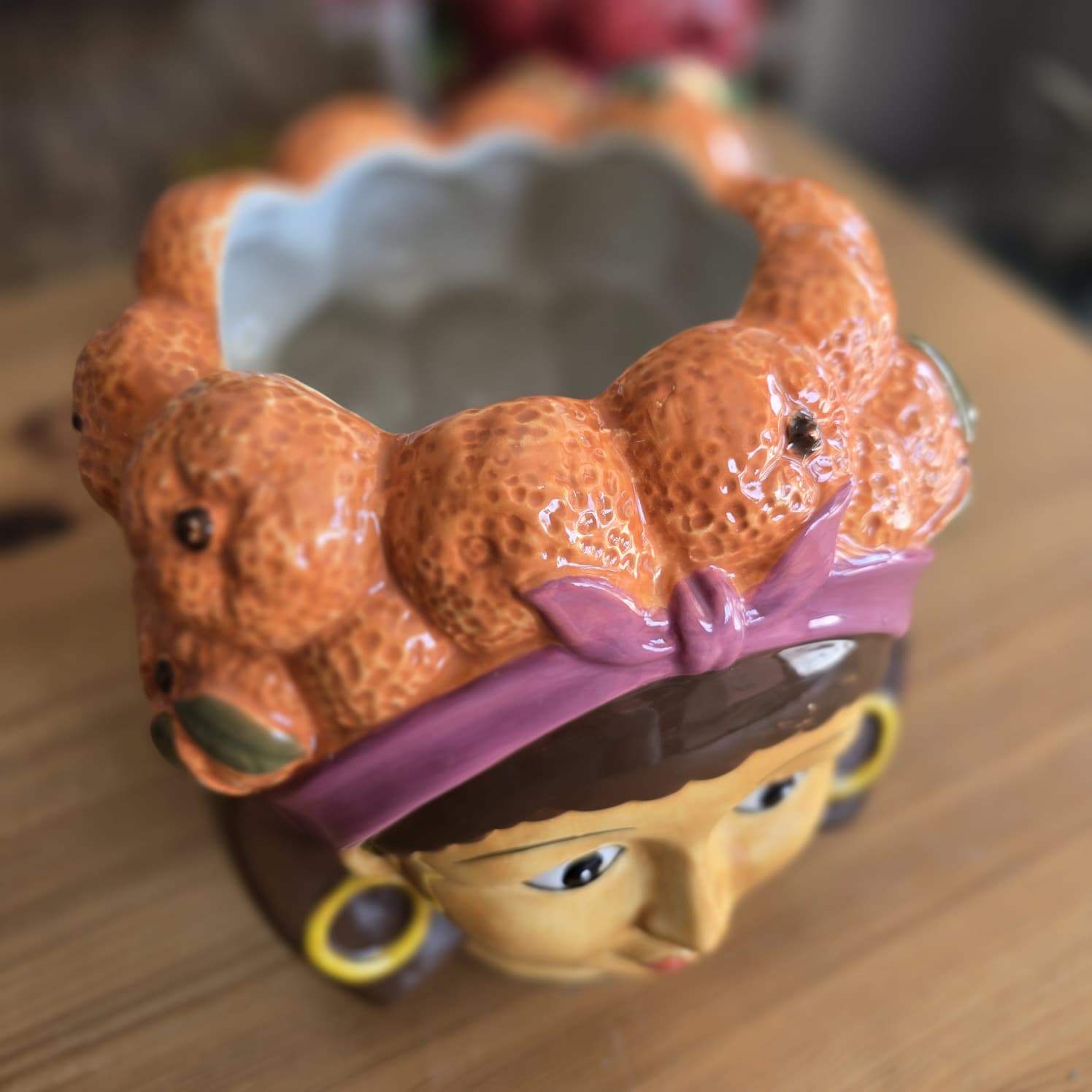 Vaso cerâmico decorativo em forma de cabeça com tangerinas no cabelo.