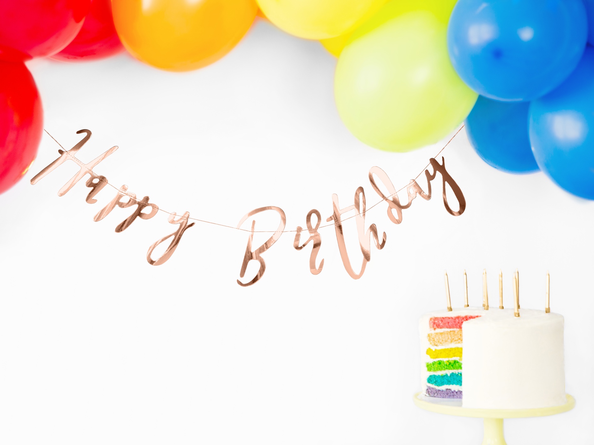 Balões coloridos e bolo de aniversário com decoração Happy Birthday