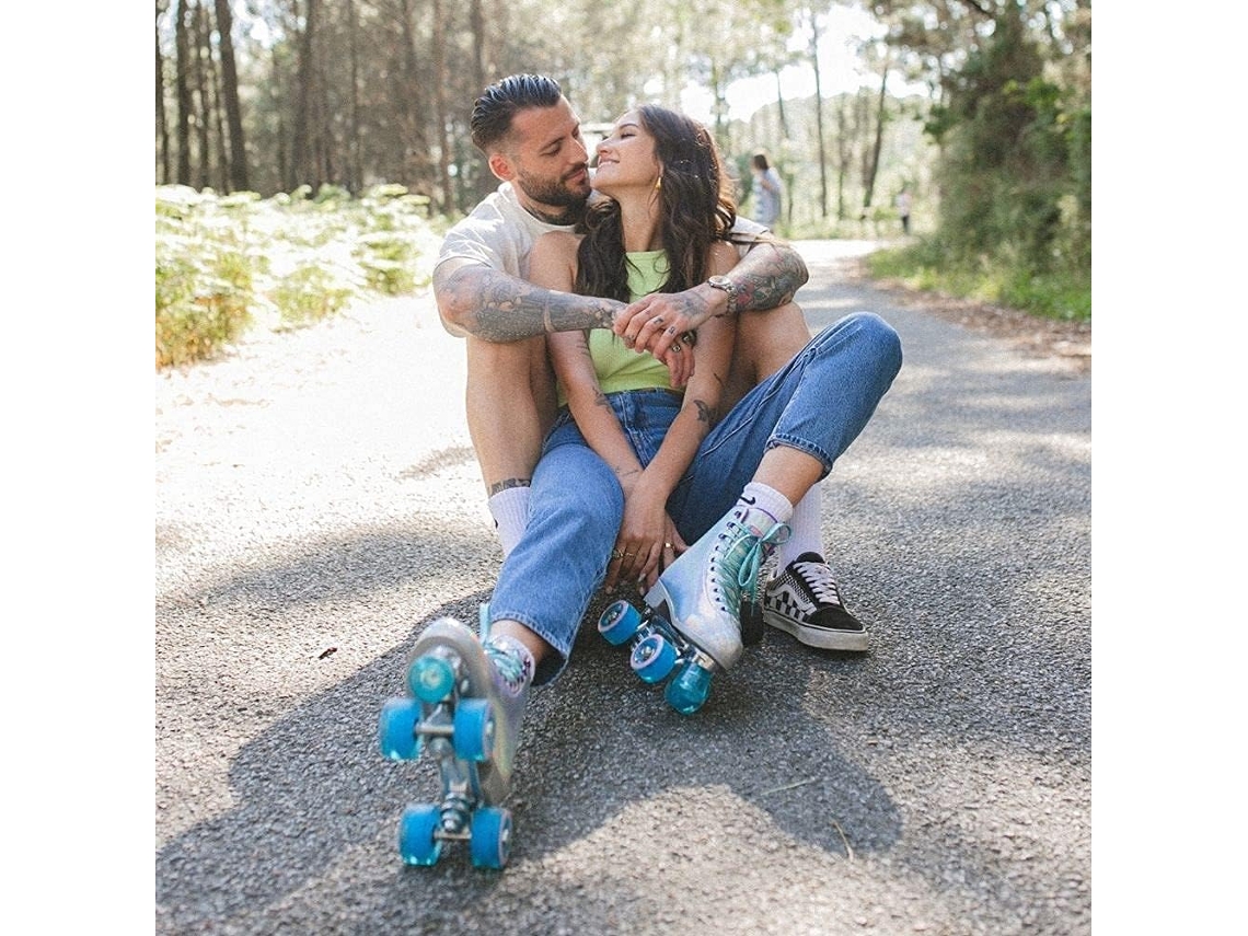 Casal sentado na estrada, mulher com patins de rodas azuis e homem com ténis