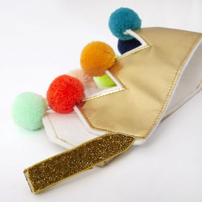 Máscara facial dourada com pompons coloridos e alça brilhante