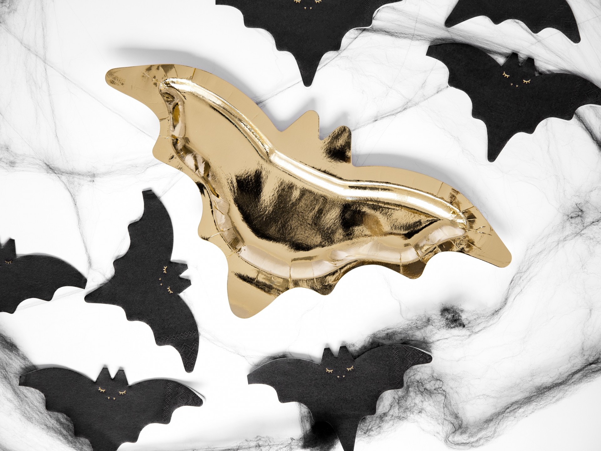 Prato dourado em forma de morcego com morcegos de papel pretos ao redor e teias de aranha decorativas