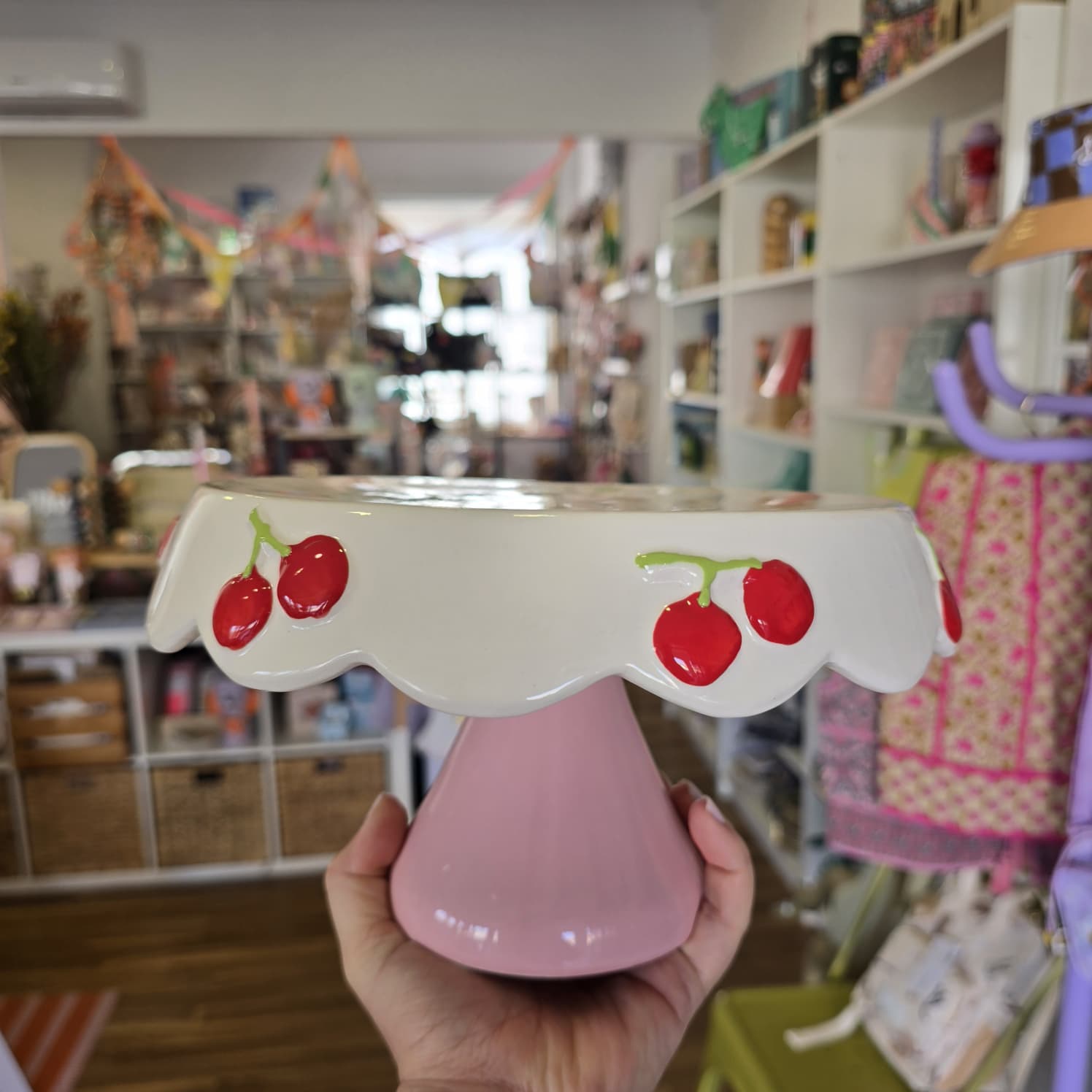 Suporte para bolo em cerâmica com base rosa e prato branco decorado com cerejas vermelhas