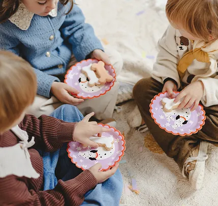 Três crianças segurando pratos decorativos com biscoitos em diferentes formas