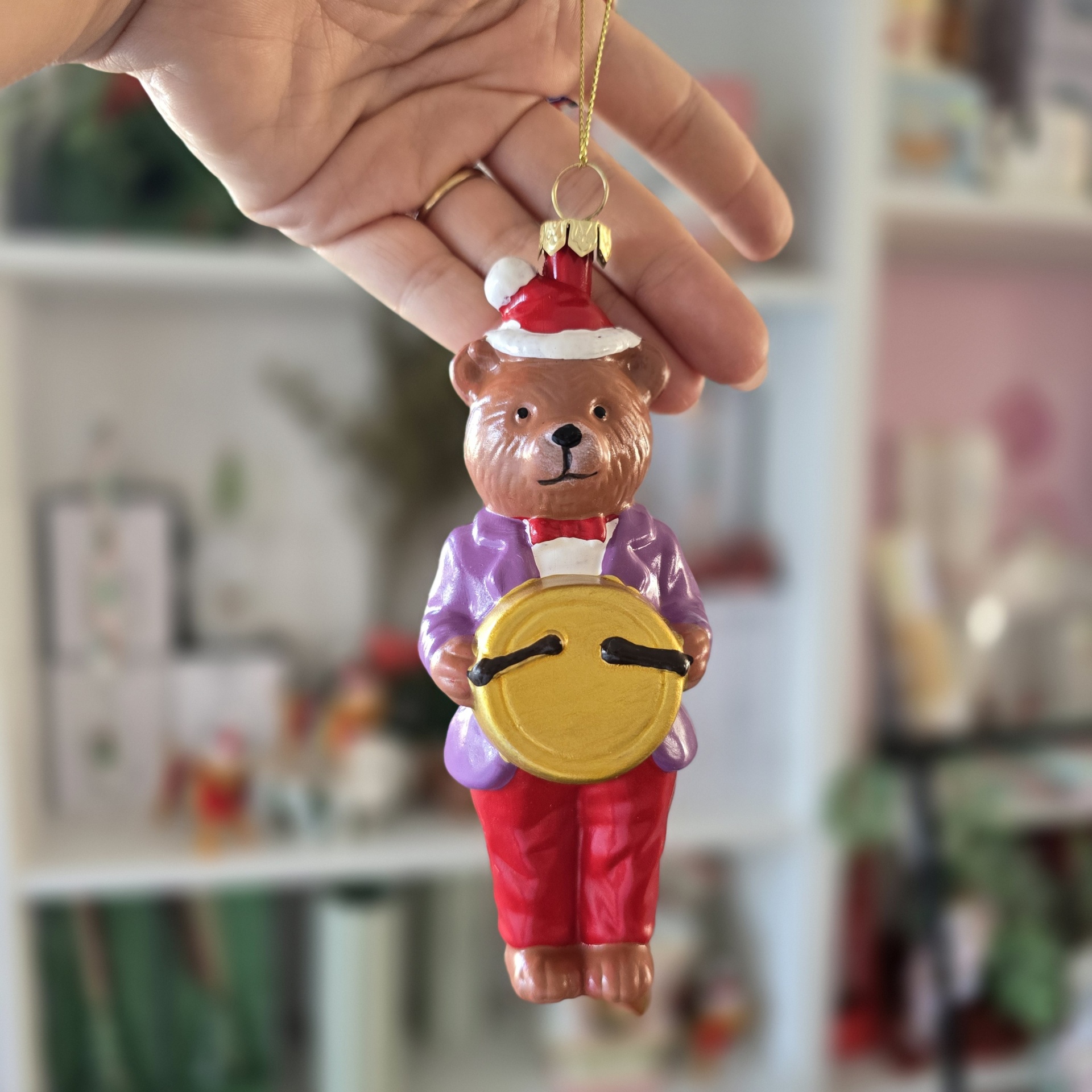 Enfeite de Natal em forma de urso castanho com chapéu de Papai Noel e roupas coloridas, a segurar um tambor amarelo