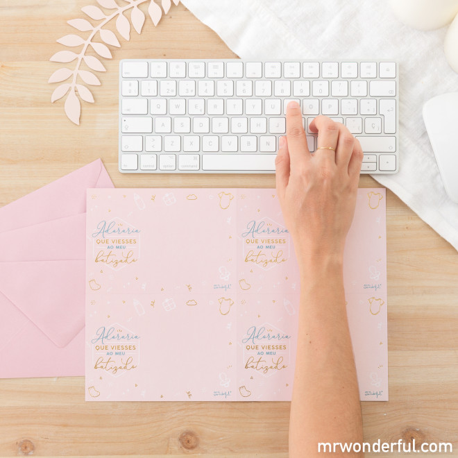 Mão a usar teclado branco sobre secretária com papel e envelope cor-de-rosa