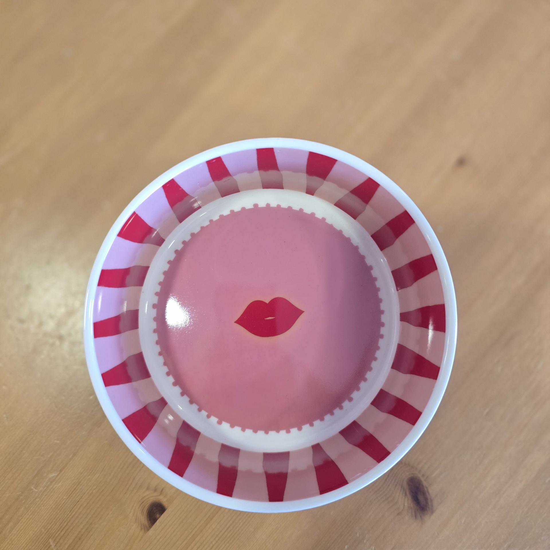 Prato redondo com riscas vermelhas e lábios vermelhos no centro
