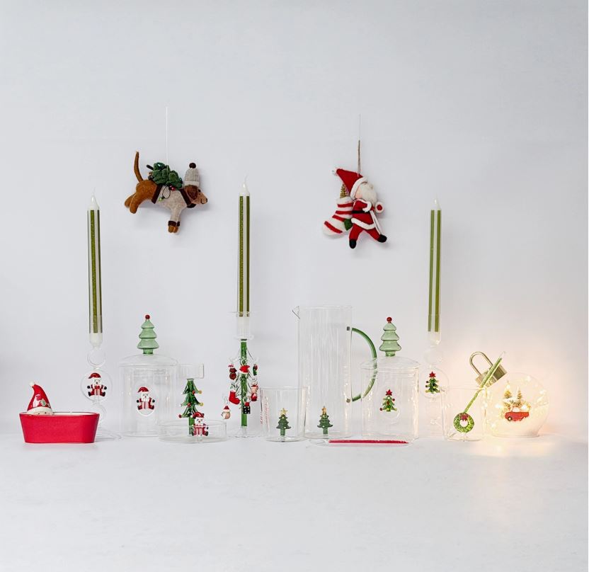 Decoração natalícia com castiçais, jarra, copos e enfeites de Pai Natal e rena