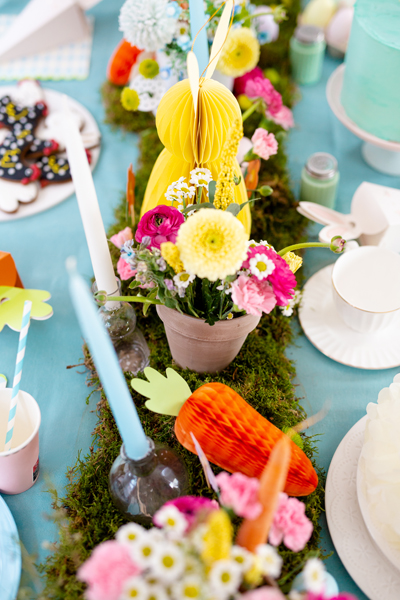 Decoração de mesa com flores coloridas, velas azuis e decoração em papel colorido