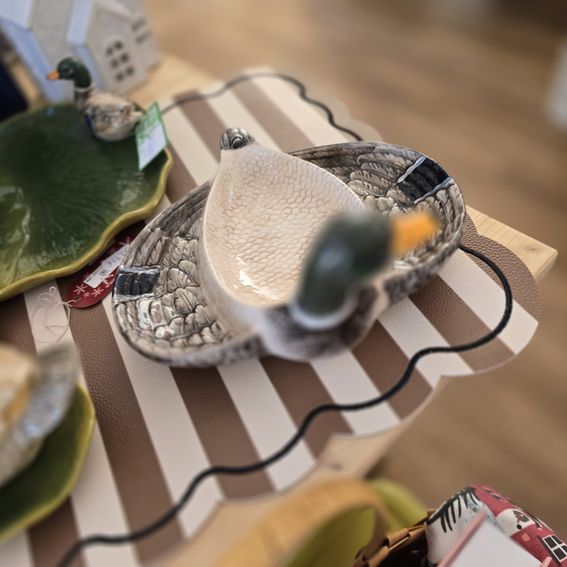 Pratos decorativos em forma de pato e prato verde em forma de folha sobre superfície listrada