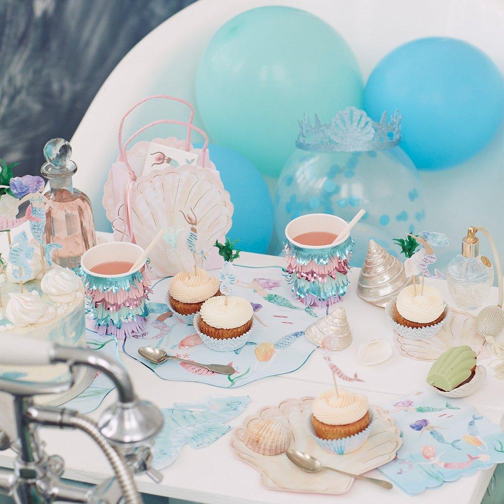 Mesa decorada com tema marinho, cupcakes, copos coloridos, balões azuis e acessórios com conchas