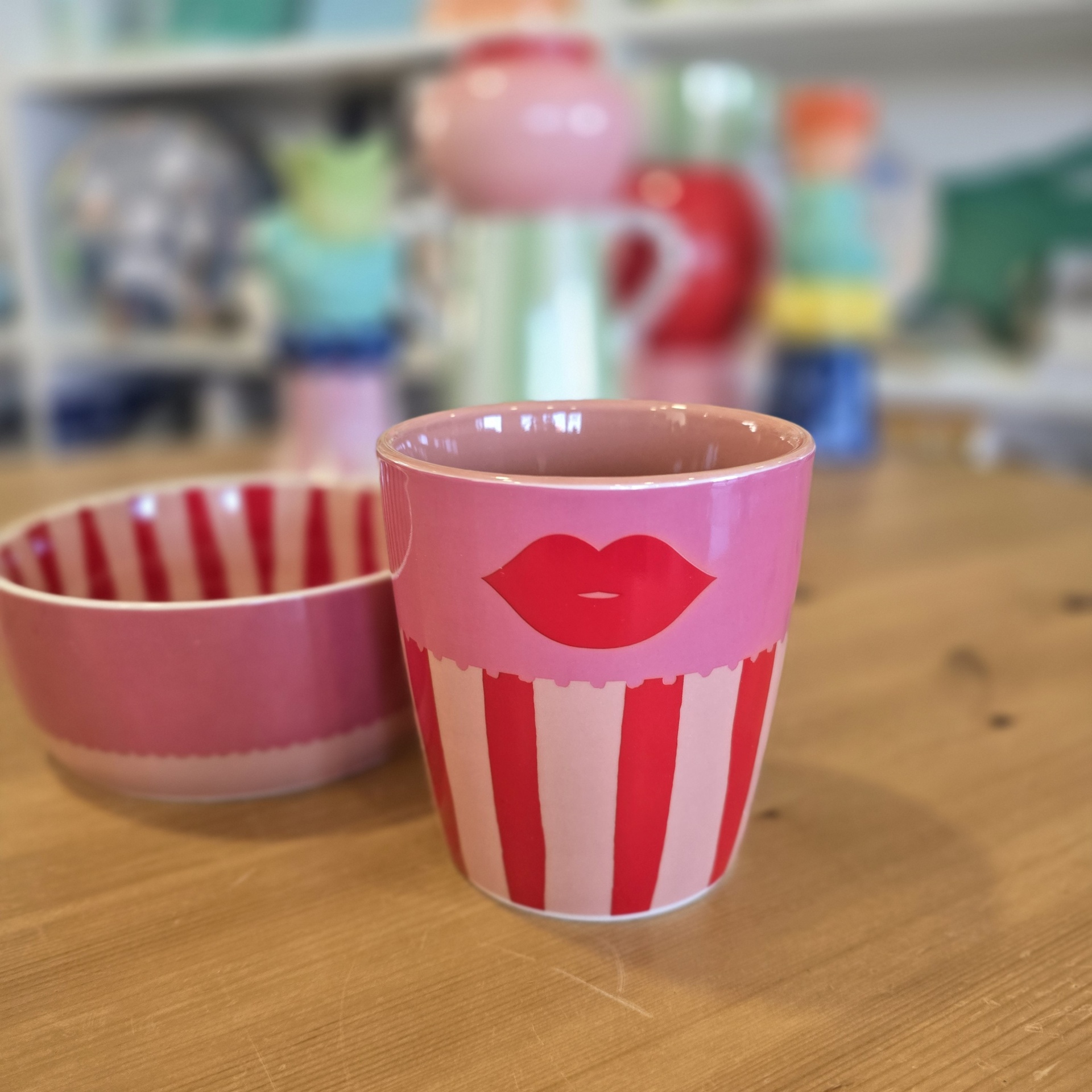 Copo e taça de cerâmica rosa e vermelho com padrão de riscas e lábios desenhados
