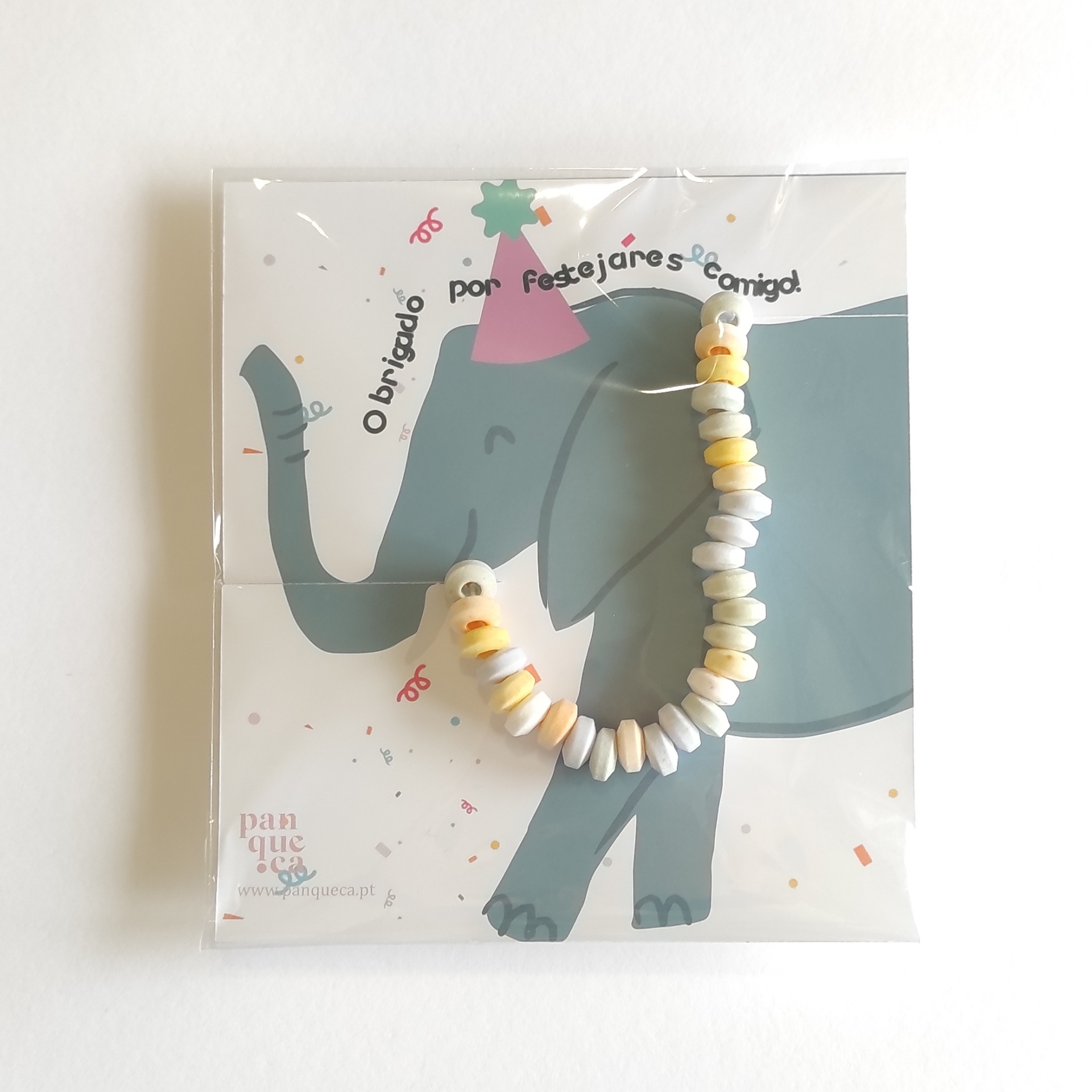 Pulseira colorida em embalagem com cartão ilustrado de elefante azul com chapéu de festa e texto de agradecimento.