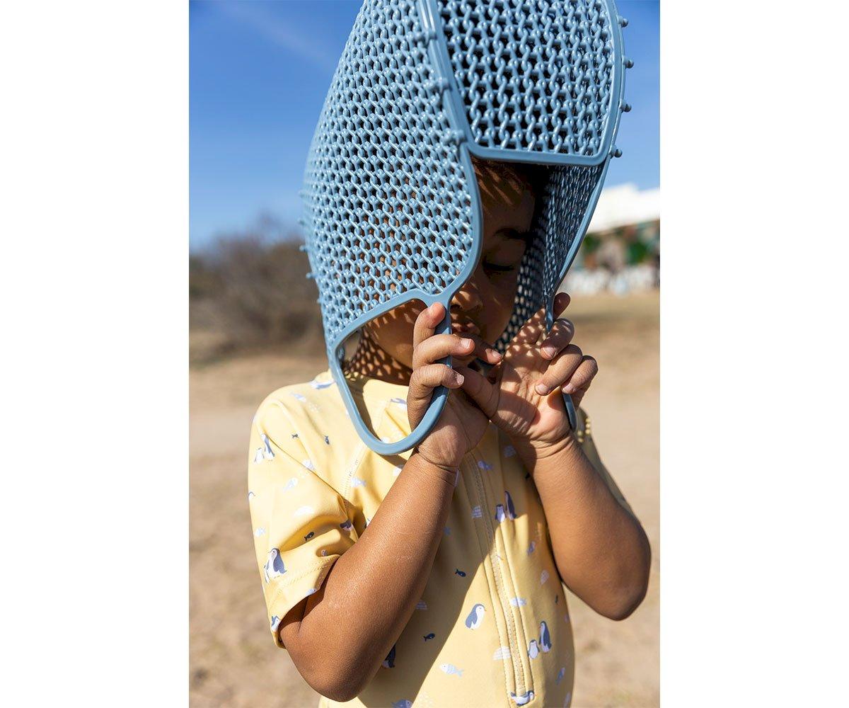 Criança com saco de plástico azul na cabeça ao ar livre