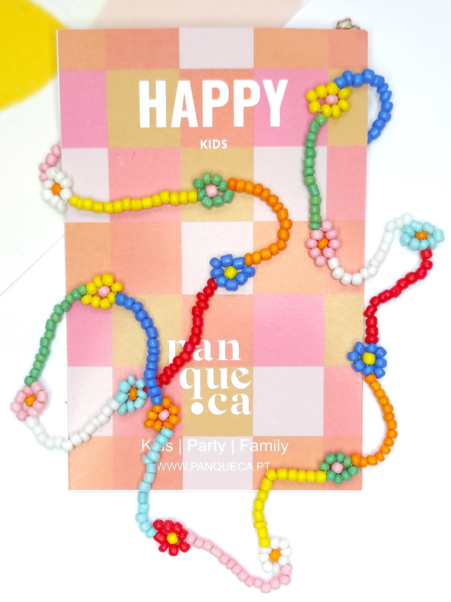 Colar infantil colorido de contas em forma de flores sobre cartão quadriculado com texto