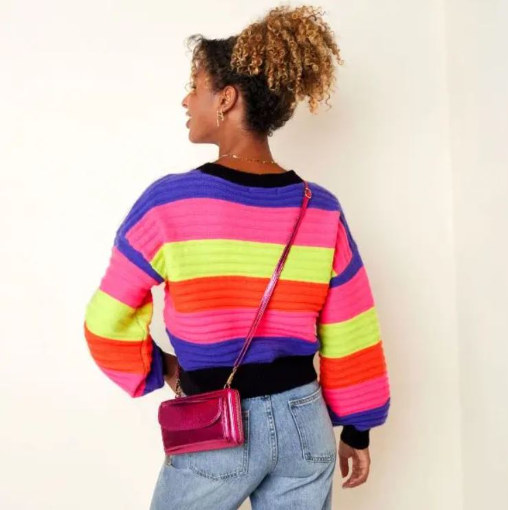 Mulher de costas com camisola colorida de malha e bolsa rosa pequena transversal